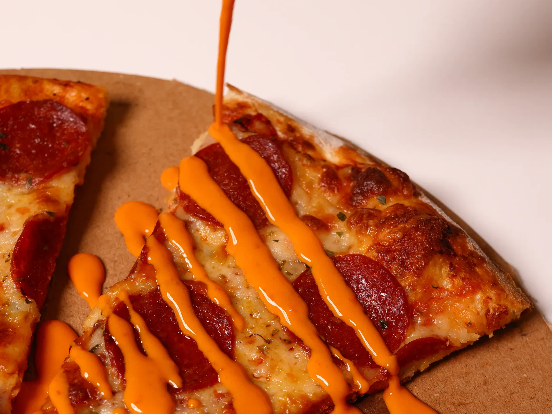 Gustego hot sauce being drizzled over a pepperoni pizza